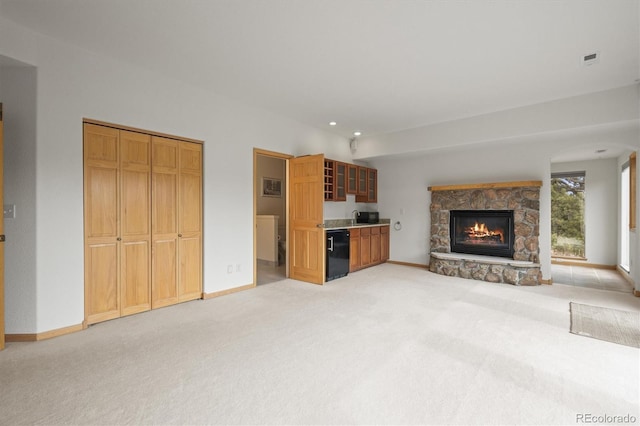 unfurnished living room featuring a fireplace, baseboards, and light carpet