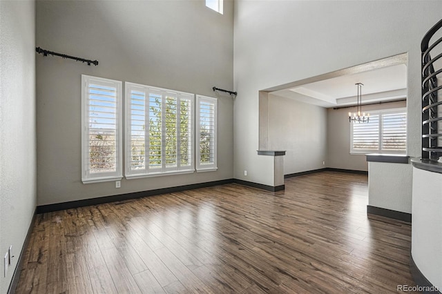 19423 W 52nd Dr, Golden, CO 80403 - unfurnished living room with a healthy amount of sunlight, dark wood-style flooring, and an inviting chandelier