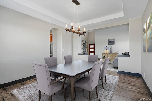 19423 W 52nd Dr, Golden, CO 80403 - dining room with a tray ceiling, baseboards, a chandelier, dark wood finished floors, and arched walkways