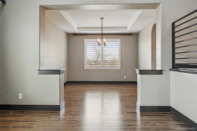 19423 W 52nd Dr, Golden, CO 80403 - unfurnished dining area with a chandelier, baseboards, wood finished floors, arched walkways, and a tray ceiling