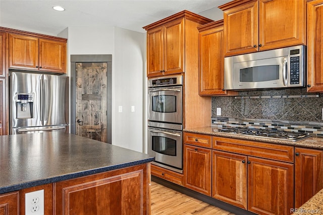 19423 W 52nd Dr, Golden, CO 80403 - kitchen with brown cabinets, decorative backsplash, and appliances with stainless steel finishes