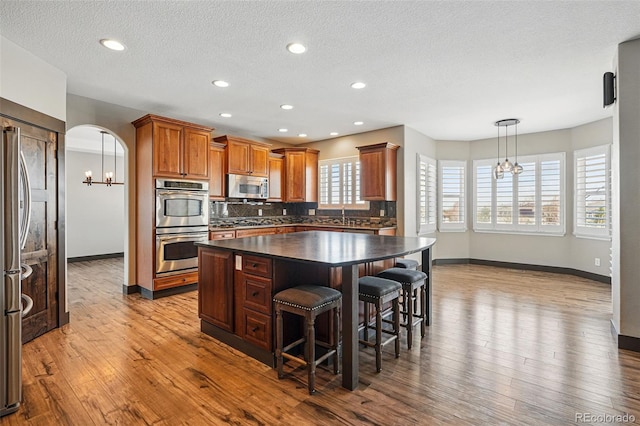 19423 W 52nd Dr, Golden, CO 80403 - kitchen featuring dark countertops, a notable chandelier, appliances with stainless steel finishes, and decorative backsplash