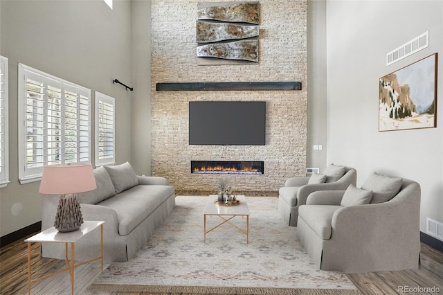 19423 W 52nd Dr, Golden, CO 80403 - living room featuring a fireplace, visible vents, a towering ceiling, and wood finished floors