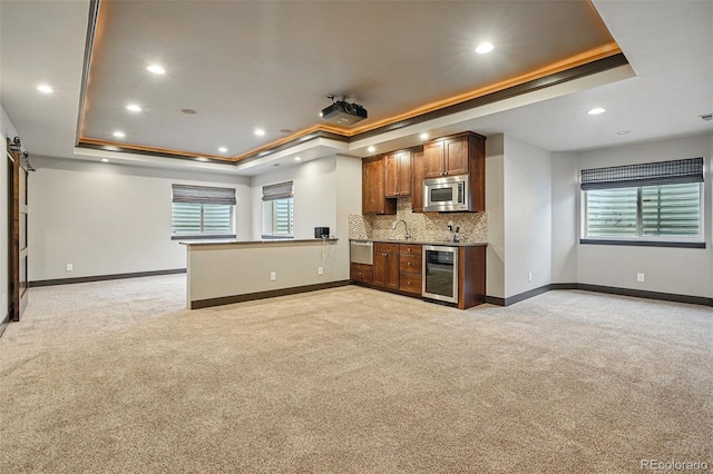 19423 W 52nd Dr, Golden, CO 80403 - kitchen with light colored carpet, stainless steel microwave, wine cooler, and a raised ceiling