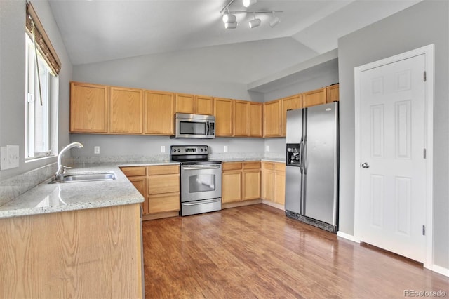 245 Homestead Way, Brighton, CO 80601 - kitchen with stainless steel appliances, vaulted ceiling, light brown cabinets, light wood-style floors, and light stone counters