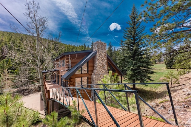 24 Pine Valley Rd, Evergreen, CO 80439 - exterior space with log exterior, a wooden deck, a chimney, and a wooded view