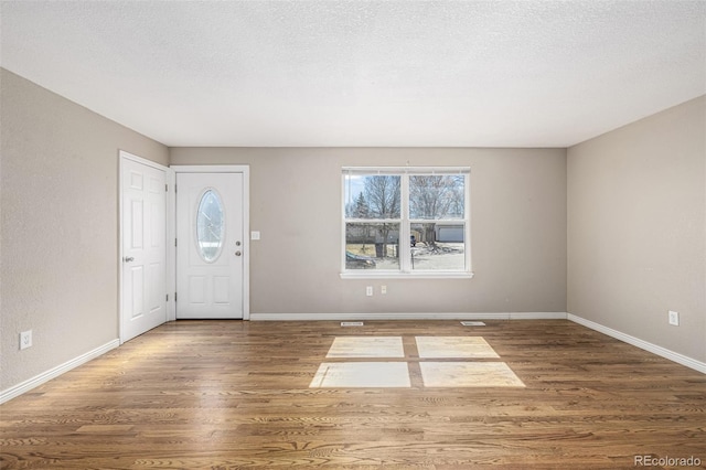 foyer featuring baseboards, a textured ceiling, and wood finished floors