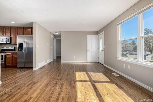 unfurnished living room with visible vents, baseboards, and dark wood-style floors