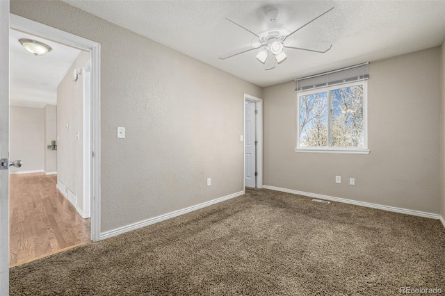 carpeted spare room featuring baseboards, visible vents, a textured ceiling, and a ceiling fan