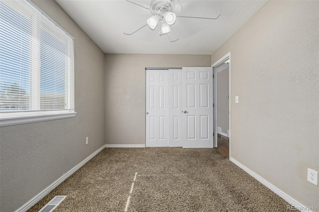 unfurnished bedroom with a closet, baseboards, a ceiling fan, and carpet flooring