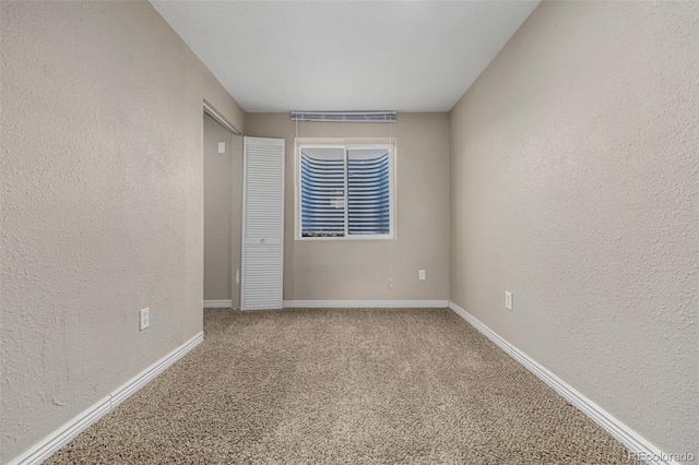 unfurnished room with baseboards, carpet flooring, and a textured wall