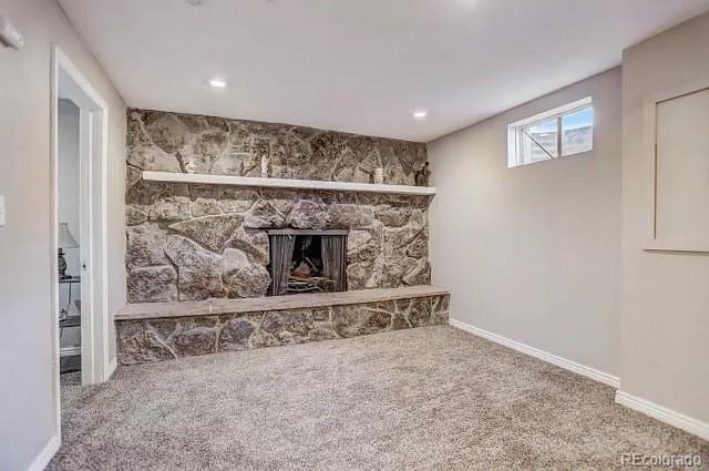 unfurnished living room with baseboards, carpet floors, and a stone fireplace