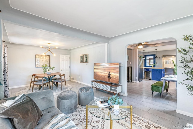 tiled living room featuring ceiling fan with notable chandelier