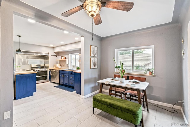 kitchen with sink, blue cabinetry, ceiling fan, appliances with stainless steel finishes, and decorative light fixtures