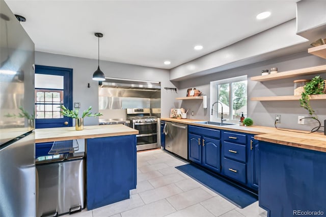 kitchen with sink, wooden counters, appliances with stainless steel finishes, blue cabinets, and decorative light fixtures