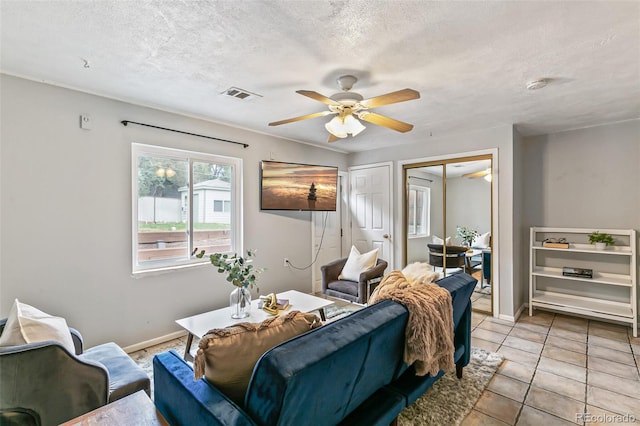 tiled living room with ceiling fan and a textured ceiling