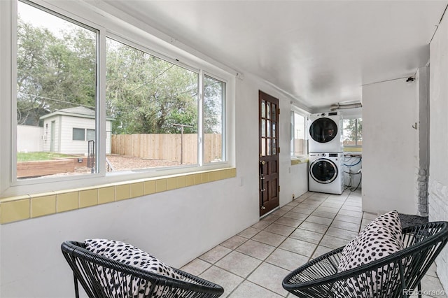 washroom featuring stacked washer and dryer, a wealth of natural light, and light tile patterned floors