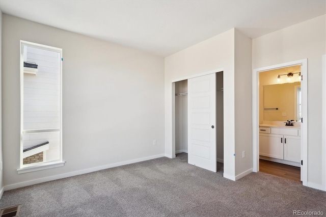 unfurnished bedroom with sink, ensuite bath, a closet, and carpet