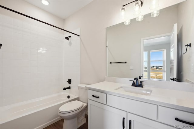 full bathroom featuring tiled shower / bath, vanity, and toilet