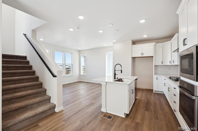 kitchen with sink, stainless steel appliances, white cabinets, and a center island with sink