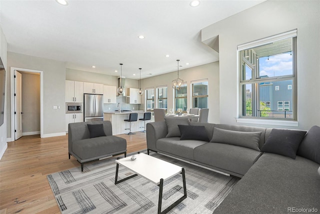 5018 S Prince Pl, Littleton, CO 80123 - living room featuring recessed lighting, plenty of natural light, light wood finished floors, and a chandelier