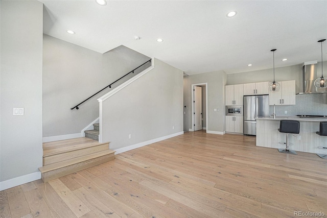 5018 S Prince Pl, Littleton, CO 80123 - unfurnished living room with light wood-style flooring, recessed lighting, and stairs