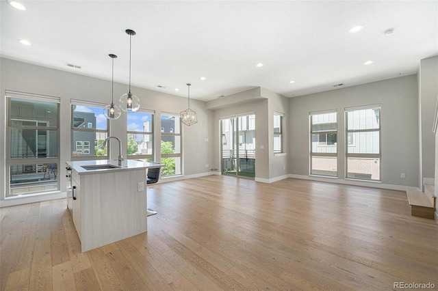 5018 S Prince Pl, Littleton, CO 80123 - kitchen featuring light wood-type flooring, healthy amount of natural light, a kitchen island with sink, recessed lighting, and open floor plan