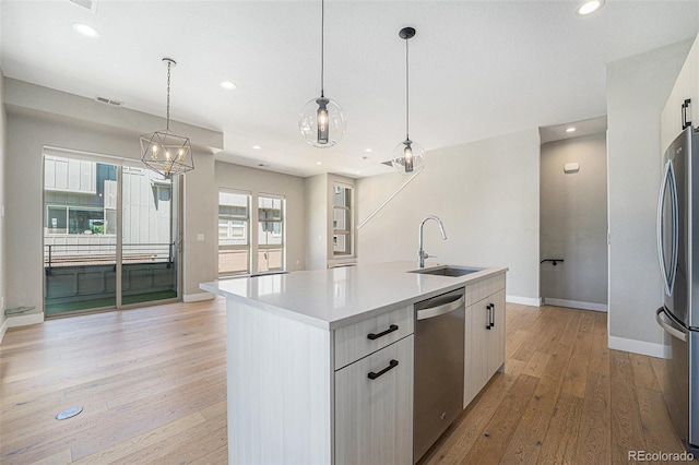 5018 S Prince Pl, Littleton, CO 80123 - kitchen with stainless steel appliances, an island with sink, light wood-style flooring, light countertops, and hanging light fixtures