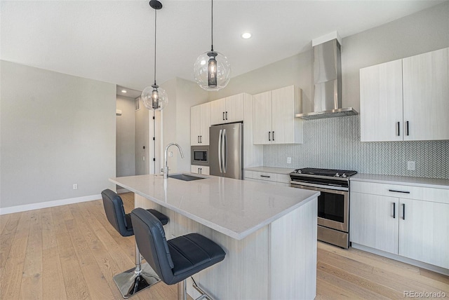 5018 S Prince Pl, Littleton, CO 80123 - kitchen with stainless steel appliances, wall chimney exhaust hood, a kitchen bar, light wood finished floors, and recessed lighting
