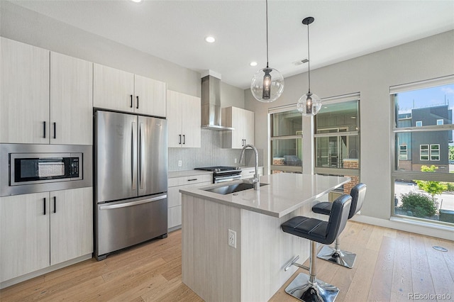 5018 S Prince Pl, Littleton, CO 80123 - kitchen featuring appliances with stainless steel finishes, wall chimney range hood, light wood-type flooring, plenty of natural light, and recessed lighting