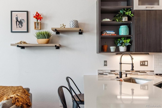 kitchen featuring sink, dark brown cabinetry, and backsplash