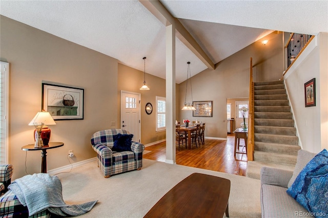 living area with beam ceiling, stairway, wood finished floors, high vaulted ceiling, and baseboards