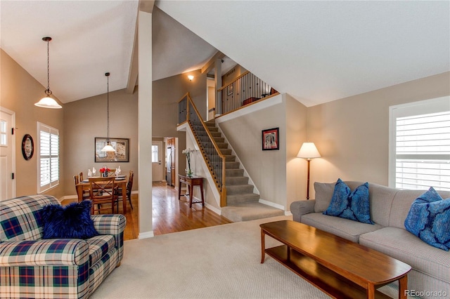 living area featuring high vaulted ceiling, baseboards, stairway, and a wealth of natural light