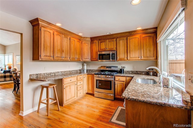 kitchen featuring appliances with stainless steel finishes, dark stone countertops, a sink, and a healthy amount of sunlight