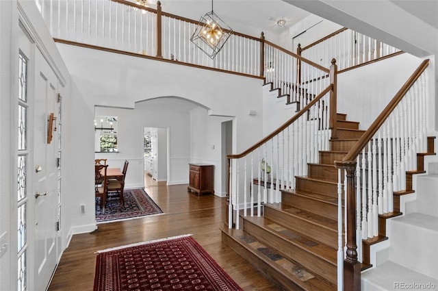 2032 W Nantucket Ct, Littleton, CO 80120 - foyer featuring arched walkways, a chandelier, wood finished floors, a towering ceiling, and stairway