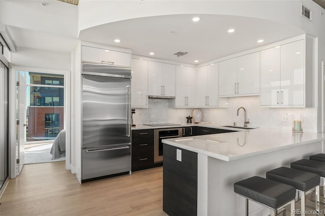 1700 Bassett St Unit 1014, Denver, CO 80202 - kitchen with stainless steel built in refrigerator, wall oven, white cabinetry, a peninsula, and a breakfast bar