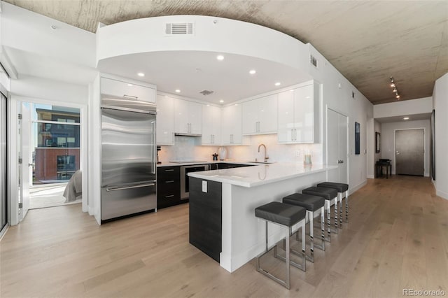 1700 Bassett St Unit 1014, Denver, CO 80202 - kitchen featuring built in refrigerator, a peninsula, white cabinets, light wood-type flooring, and a breakfast bar