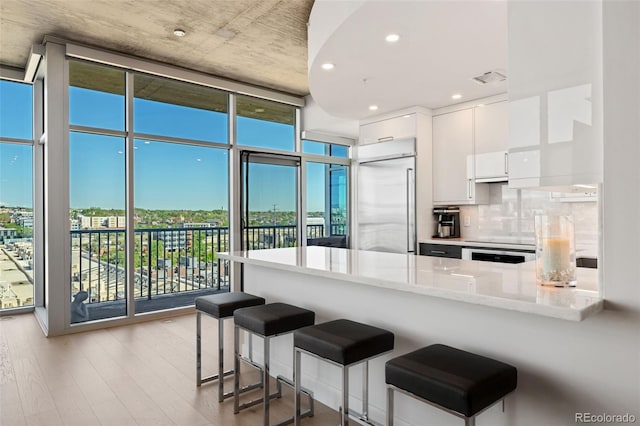 1700 Bassett St Unit 1014, Denver, CO 80202 - kitchen featuring stainless steel built in refrigerator, expansive windows, a peninsula, wood finished floors, and white cabinetry