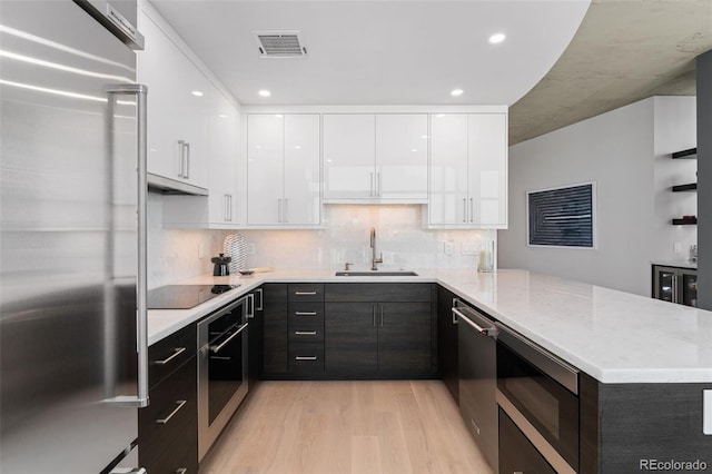 1700 Bassett St Unit 1014, Denver, CO 80202 - kitchen with stainless steel appliances, modern cabinets, light wood-style flooring, white cabinetry, and a peninsula