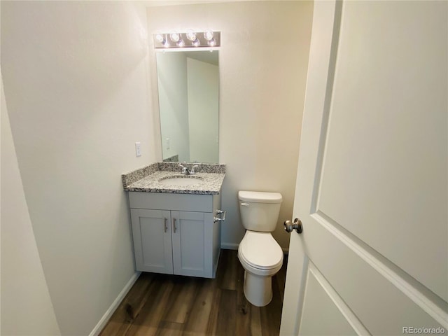 45016 Sunflower Ln, Bennett, CO 80102 - half bathroom featuring vanity, wood finished floors, toilet, and baseboards