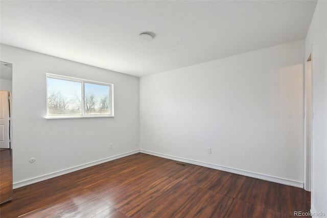 empty room featuring baseboards and dark wood-style floors