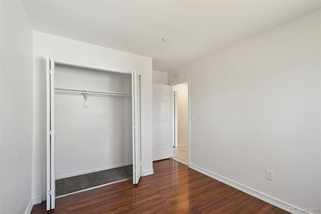 unfurnished bedroom with a closet, baseboards, and wood finished floors