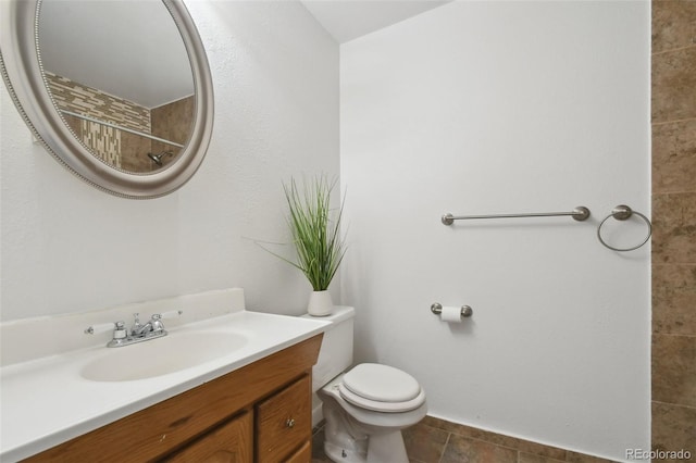 bathroom with toilet, vanity, and a tile shower