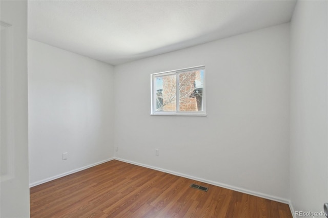 unfurnished room with wood finished floors, visible vents, and baseboards