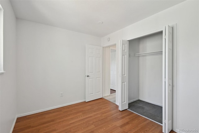 unfurnished bedroom with wood finished floors, a closet, and baseboards