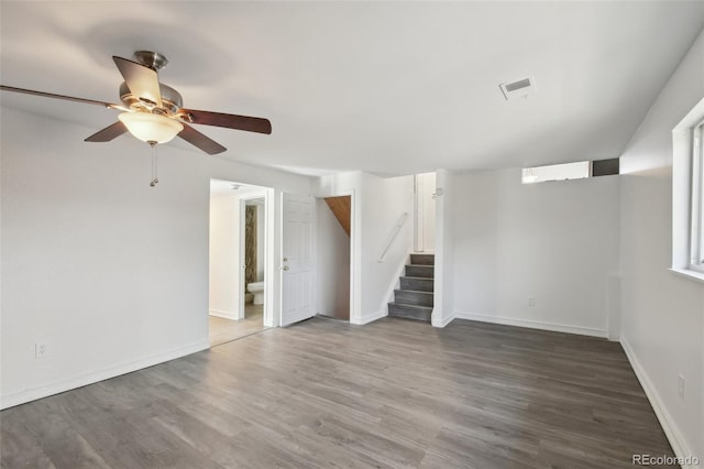 unfurnished living room with visible vents, wood finished floors, baseboards, ceiling fan, and stairs