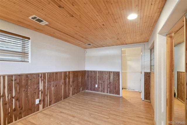 spare room featuring visible vents, a wainscoted wall, wood walls, wood ceiling, and wood finished floors