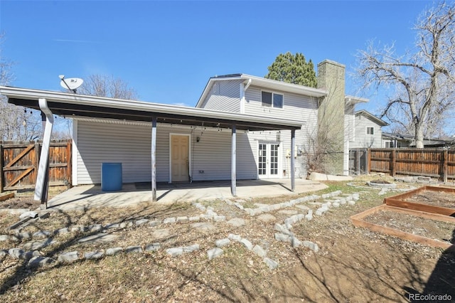 rear view of property featuring a patio area, a vegetable garden, fence, and a chimney