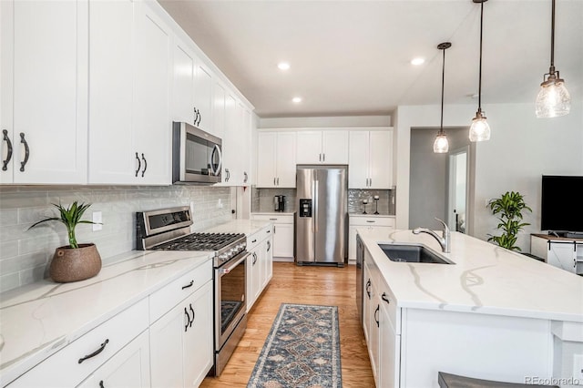 kitchen featuring light wood-type flooring, white cabinetry, a kitchen island with sink, a sink, and stainless steel appliances