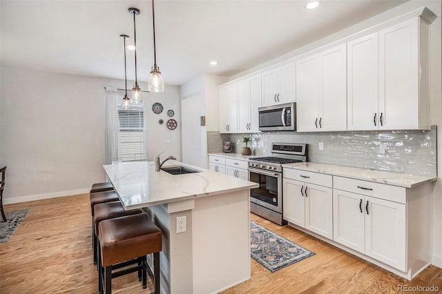 kitchen with light wood-style flooring, white cabinetry, appliances with stainless steel finishes, a sink, and backsplash